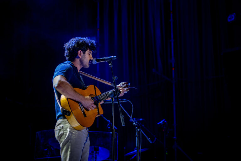 Juan Gallardo cantando con su guitarra española bajo una luz azul en el Pop CAAC 2026 de Sevilla