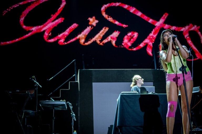Ouineta cantando en el escenario del Pop CAAC 2026 de Sevilla con su nombre en neón rosa al fondo