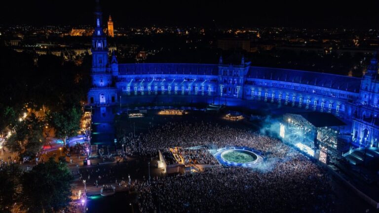Vista aérea de noche de la Plaza de España de Sevilla llena de público durante un concierto de Icónica Sevilla Fest, con la Giralda al fondo