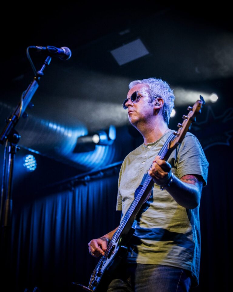 El bajista de Ocean Colour Scene tocando bajo los focos azules en el concierto de Sevilla
