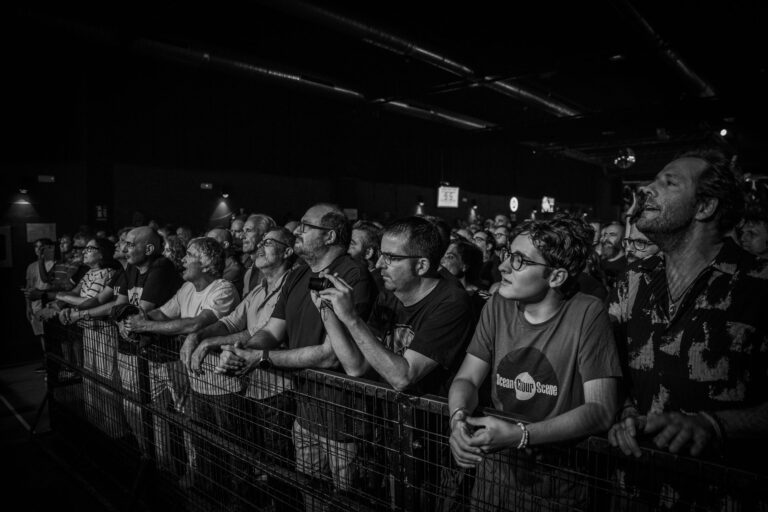 Público apoyado en la valla de la primera fila en el concierto de Ocean Colour Scene en Sevilla, con un chico joven con la camiseta del grupo