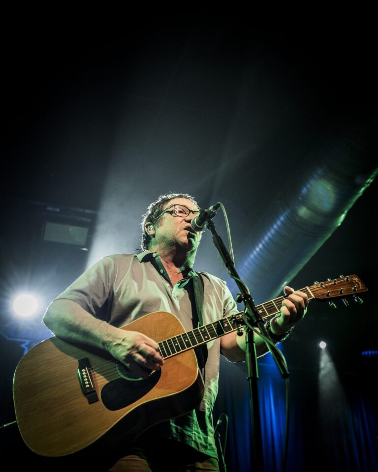 Simon Fowler a contraluz con la guitarra acústica en el escenario de la Sala Custom de Sevilla