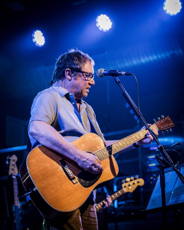 Simon Fowler con su guitarra acústica bajo los focos azules en el concierto de Ocean Colour Scene en Sevilla