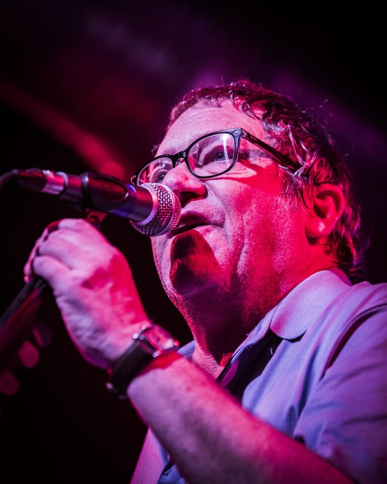Primer plano de Simon Fowler cantando al micrófono bajo luz roja en la Sala Custom de Sevilla