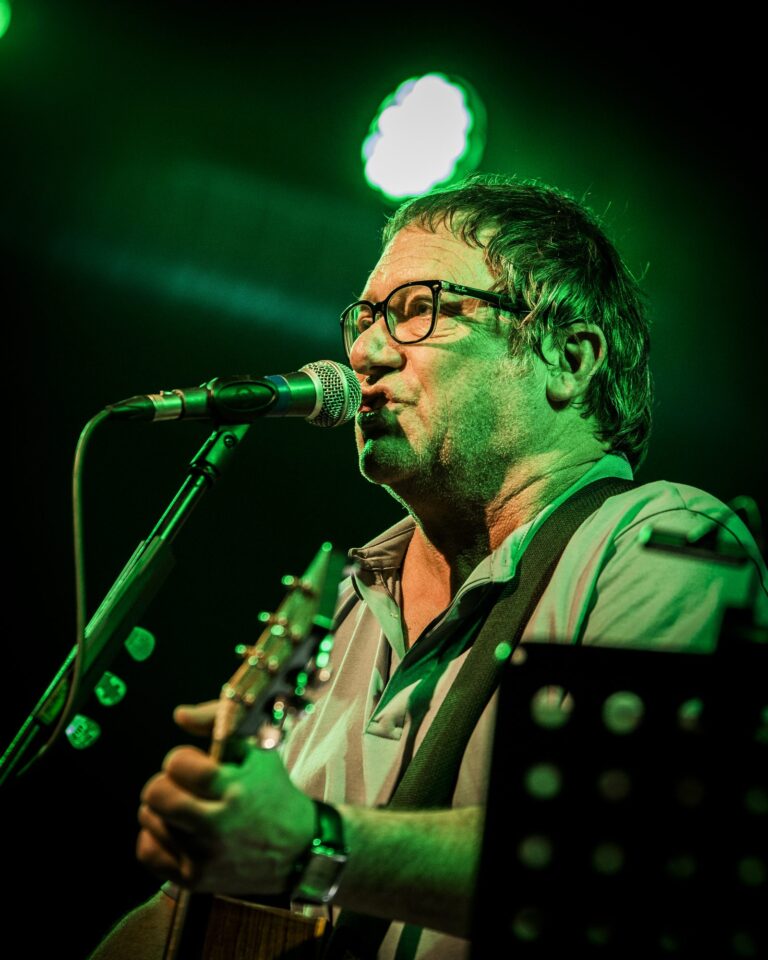 Primer plano de Simon Fowler cantando con gafas bajo un foco verde en el concierto de Ocean Colour Scene en Sevilla