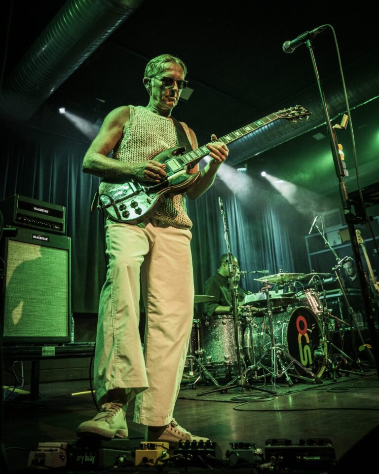 Steve Cradock de cuerpo entero con la guitarra y el bombo de Ocean Colour Scene detrás en la Sala Custom de Sevilla