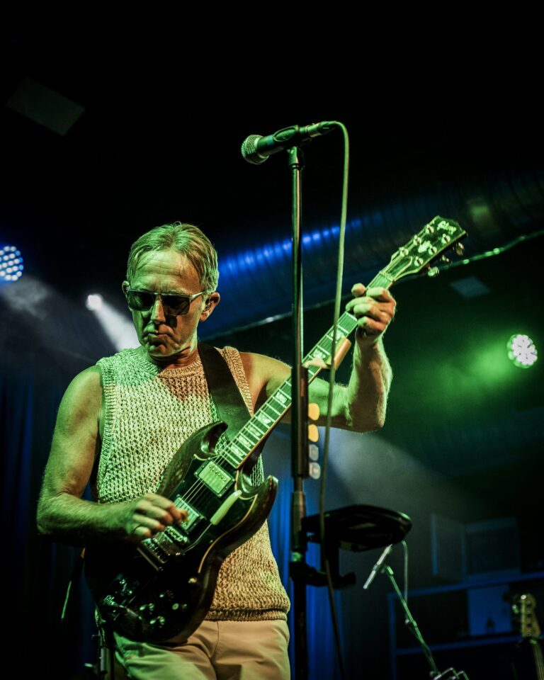 Steve Cradock tocando la guitarra eléctrica bajo luces verdes y azules en la Sala Custom de Sevilla