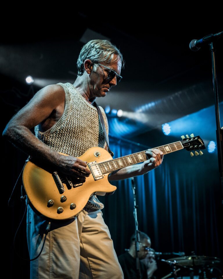 Steve Cradock tocando una Les Paul dorada bajo luz azul en el concierto de Ocean Colour Scene en Sevilla