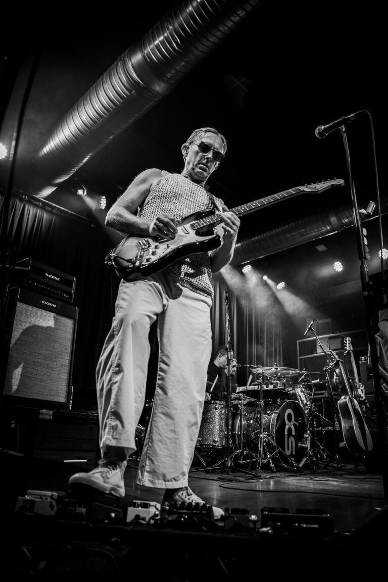 Steve Cradock tocando una Stratocaster desde un ángulo bajo, en blanco y negro, en el concierto de Ocean Colour Scene en Sevilla